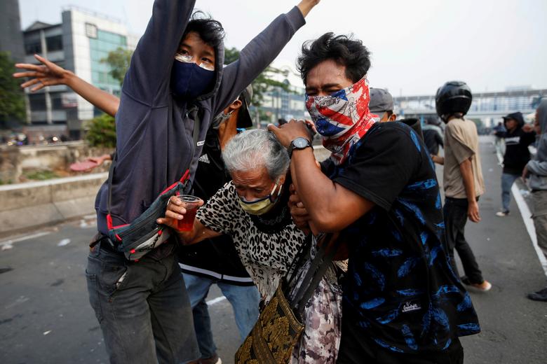 Индонезия. Протестующие защищают летнюю женщину во время столкновений с полицией в рамках протестов против трудовой реформы / октябрь 2020 / Reuters