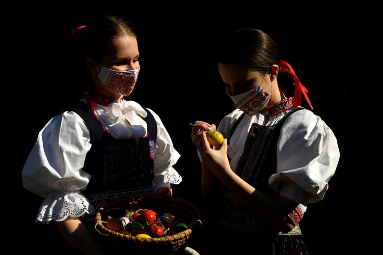 Словаччина. Дівчата у національних костюмах і масках розфарбовують крашанки напередодні Великодня / квітень 2020 року / Reuters