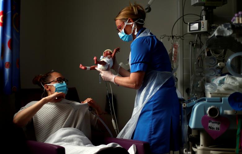 Соединенное Королевство. Неонатолог передает преждевременно родившегося младенца на руки матери в отделении интенсивной терапии новорожденных в больнице Бернли / май 2020 / Reuters