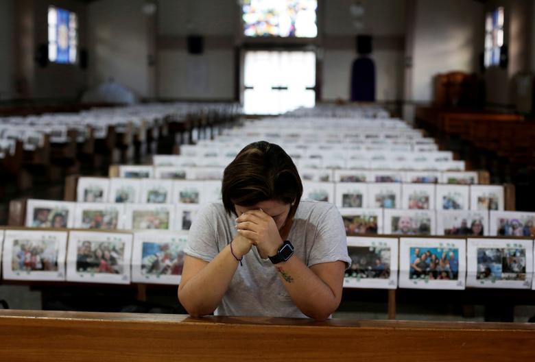 Коста-Ріка. Католичка Адріана Бренз молиться під час онлайн-трансляції меси поряд з фото інших прихожан, розміщеними над церковними лавками, через пандемію короновірусу / квітень 2020 року / Reuters