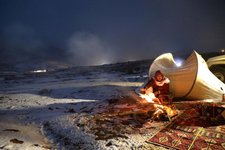 Саудівська Аравія. Чоловік поряд з наметом намагається зігрітися після снігопаду / лютий 2020 року / Reuters