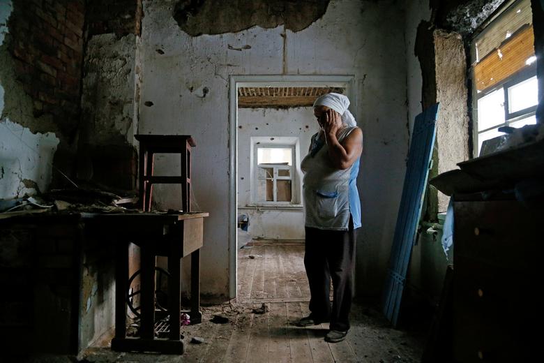 Україна. 77-річна Катерина Ізвекова демонструє знищений будинок. Reuters пише про “конфлікт між військами самопроголошеної ДНР” та ЗСУ поблизу лінії розмежування у підконтрольному окупантам селі Веселе / липень 2020 року / Reuters
