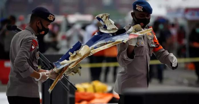 Индонезийские полицейские несут обломки самолета, фото: Reuters