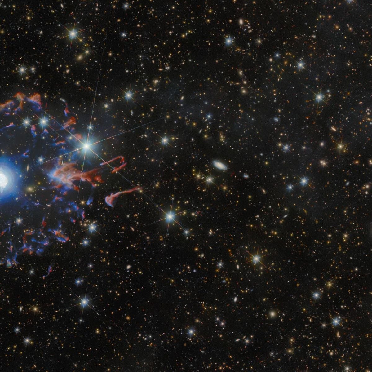 Планетарна туманність у космосі. Зірка в самому центрі оточена білими бульбашками і петлями газу, які сяють потужним блакитним світлом. Далі від неї туманність оточує розірване кільце червоних і блакитних газових хмар. Безліч золотих і білих зірок, пасма газу і віддалені галактики різних розмірів оточують туманність на чорному тлі. Джерело: ESA/Hubble & NASA, ESA Euclid/Euclid Consortium/NASA/Q1-2025, J.-C. Cuillandre & E. Bertin (CEA Paris-Saclay), Z. Tsvetanov